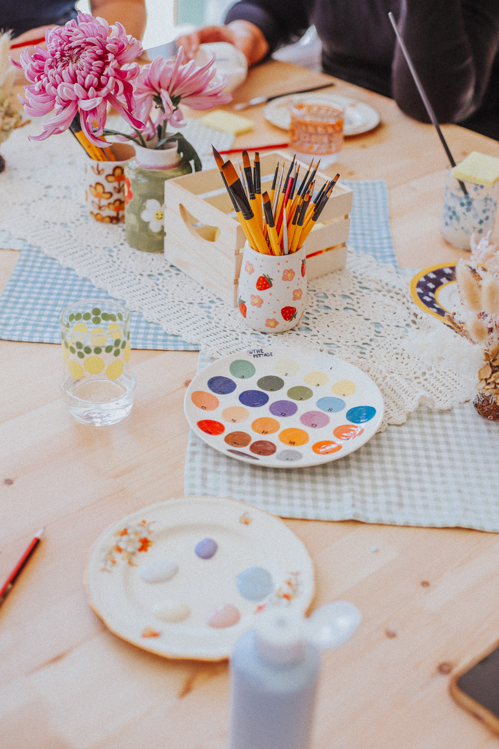 A table at the pottage with various ceramics and paints on it